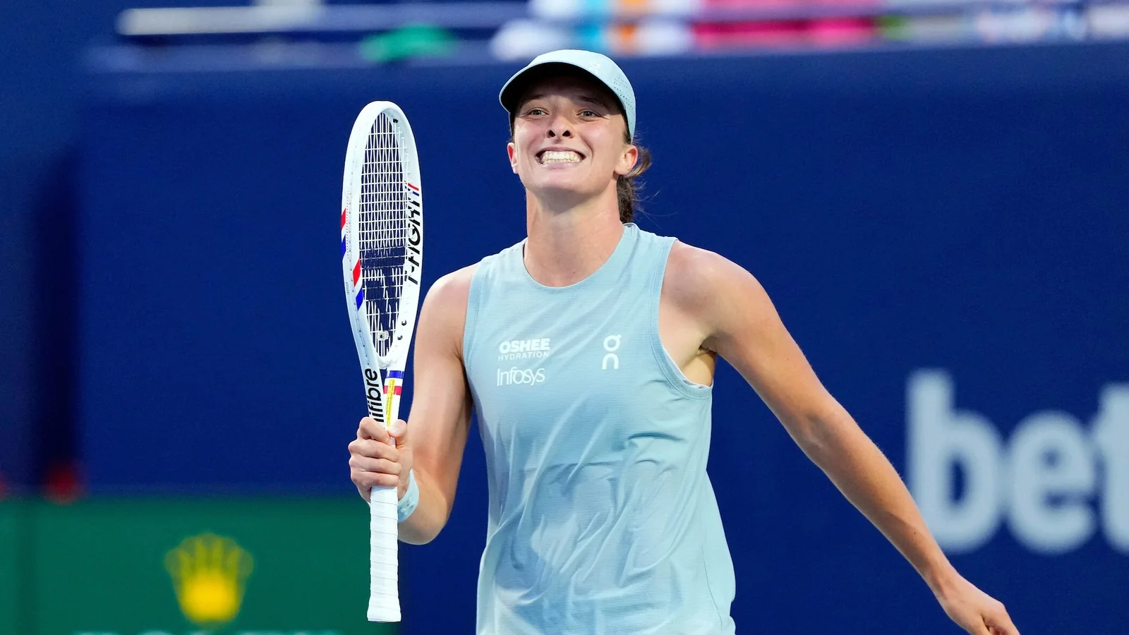 Iga Swiatek smiles with her racket on the blue court in Toronto in 2026