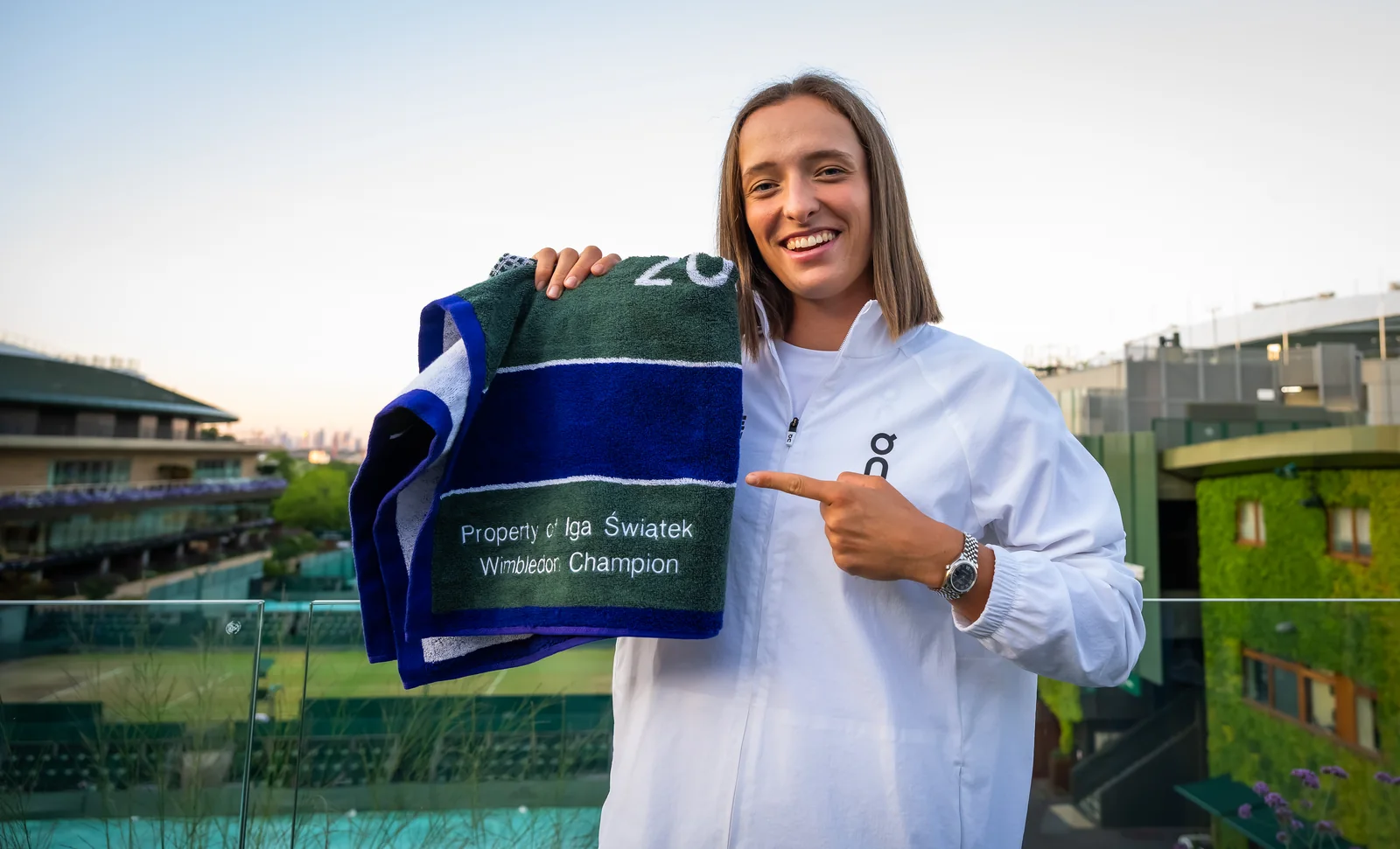 Iga Swiatek holding a Wimbledon champion towel after the 2025 tournament