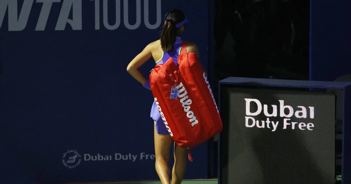 Player carrying tennis equipment beside Dubai Duty Free tournament signage